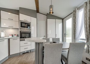 Una cocina moderna con electrodomésticos integrados, una mesa de comedor con sillas y un amplio ventanal con cortinas.