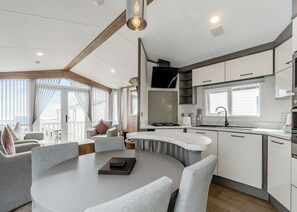 Una cocina moderna con una isla curva, un comedor con mesa redonda y vistas al mar a través de grandes ventanales.