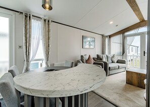 Un moderno salón con una mesa de centro de mármol, sofás grises y vistas al exterior.
