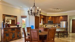 A spacious kitchen with wooden cabinets, a central island, and a dining area with a chandelier. - Depa in EDM first floor beachfront By GPS (Mazatlán)