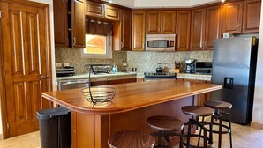 Cucina con mobili in legno, frigorifero in acciaio inossidabile, forno a microonde e piano di lavoro in granito.