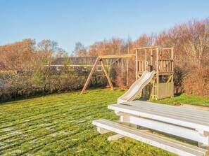A playground with a slide and swings, surrounded by a grassy area and trees. - 4 Star Holiday Home in Hemmet (Hemmet)