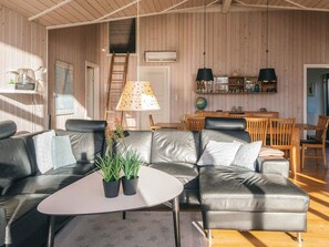 A modern living room with a leather sofa, a small white table, and a wooden dining area with chairs. - 4 Star Holiday Home in Hemmet (Hemmet)