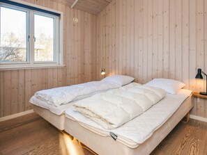A bedroom with a wooden floor, a bed with white bedding, a nightstand with a lamp, and a window with blinds. - 4 Star Holiday Home in Hemmet (Hemmet)