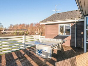 A deck with a table and chairs, a play structure, and a house with a tiled roof and a satellite dish. - 4 Star Holiday Home in Hemmet (Hemmet)