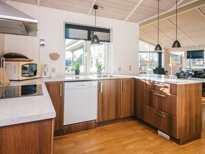 A modern kitchen with wooden cabinets, a built-in dishwasher, and pendant lighting. - 4 Star Holiday Home in Hemmet (Hemmet)