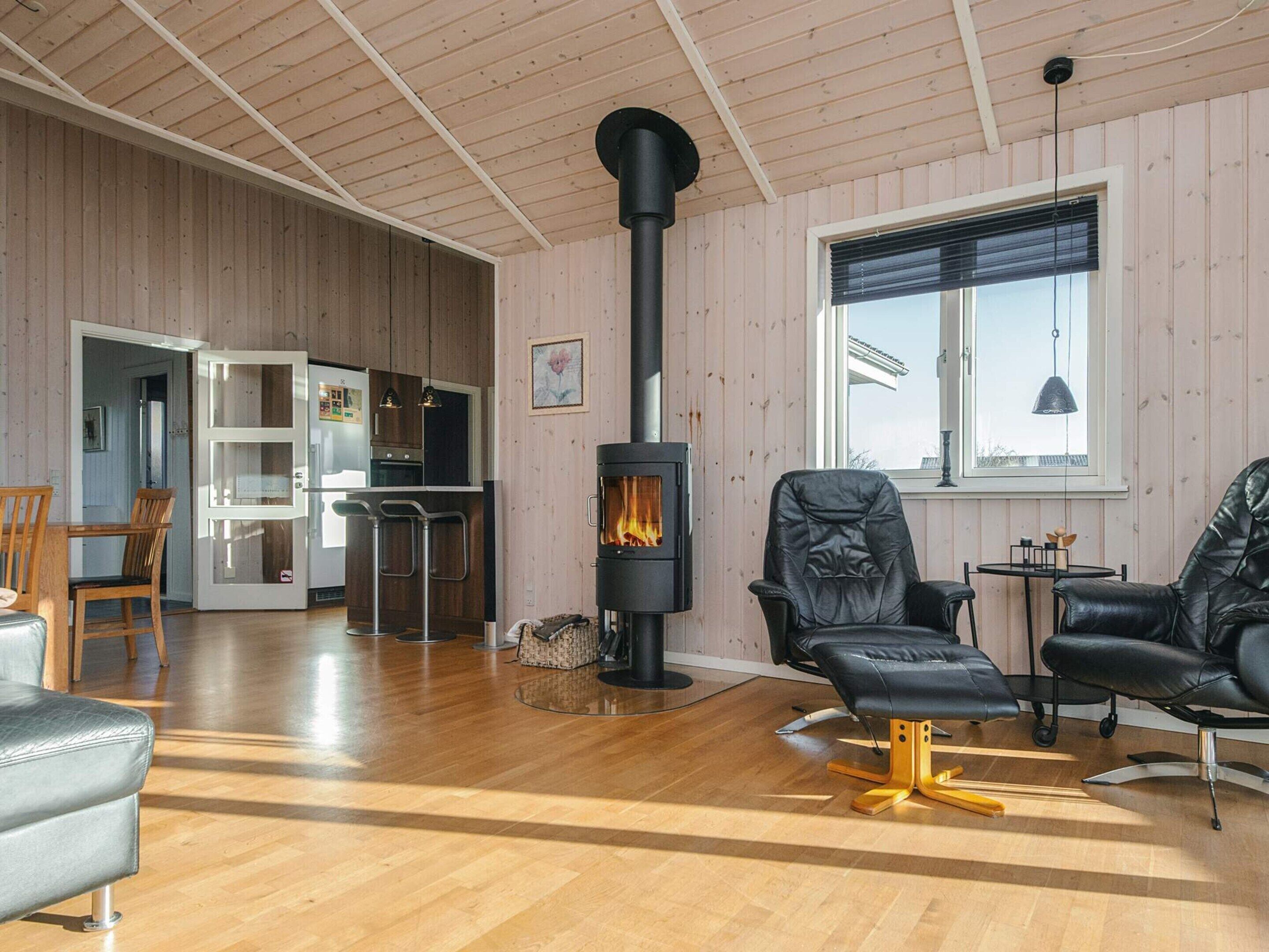 A cozy living room with a fireplace, wooden floors, and a view of the outside.