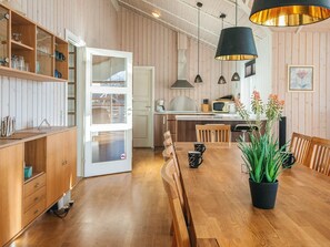 A modern kitchen with wooden cabinetry, a dining table with chairs, and pendant lighting. - 4 Star Holiday Home in Hemmet (Hemmet)