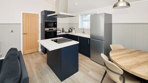 Et kompakt køkken med en central ø, indbygget ovn og et køleskab.