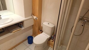 Et badeværelse med toilet, vask og brusebad.