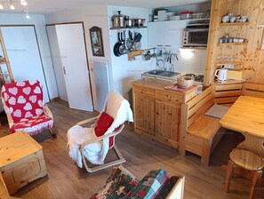 Una cocina acogedora con armarios de madera, una mesa de comedor y una silla con cojín rojo.