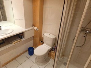 Un baño pequeño con inodoro, lavamanos y ducha.