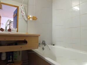 A bathroom with a white bathtub, a wooden vanity, and a mirror. - Paradiski ski in ski out vallandry (LANDRY)
