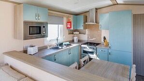A compact kitchen with a microwave, stove, sink, and cabinets.