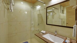 Ein modernes Badezimmer mit einer Duschkabine aus Glas, einem großen Spiegel und einem Waschbecken mit Granitplatte.