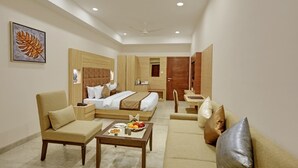 Ein Hotelzimmer mit einem Bett, zwei Sofas, einem Couchtisch und einem Esstisch.