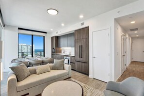 Um apartamento moderno com área de refeições, cozinha compacta e sofá.
