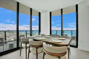 Un comedor con una mesa lista para cuatro, ventanas amplias y vistas a la ciudad y al mar.