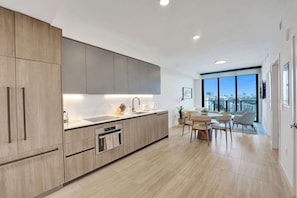 A modern kitchen with a built-in oven, a sink, and a dining area with a table and chairs.
