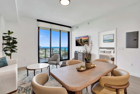 Uma sala de estar moderna com área de refeições, janelas grandes e vista da cidade.