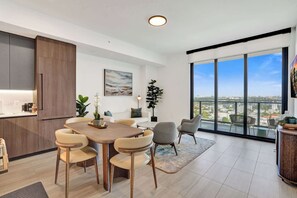 Une cuisine moderne avec un coin repas, de grandes fenêtres et une vue sur la ville.