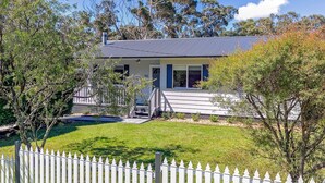 A two-story house with a covered porch, a fenced yard, and trees. - Tranquil Haven The Perfect Blue Mountains Escape (KATOOMBA)