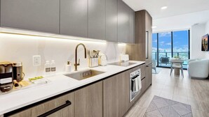 A modern kitchen with a large island, built-in appliances, and a view to the outside. - Penthouse Perfect | 2BR/2BA, Ocean Air & Views (Miami Beach)