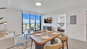 A modern dining area with a large table set for six, a sofa, and a view of the cityscape. - Penthouse Bright 2BR | Miami Beach at Its Best (Miami Beach)