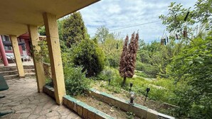 A stone-paved patio with a covered area, surrounded by lush greenery and a variety of plants. - Oceonviev Retreat (Varna)