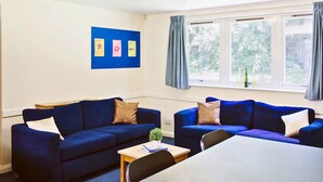 A room with two blue sofas, a small table, and a window with curtains. - For Students Only Queen's Hospital Close near Birmingham City Centre (Birmingham)