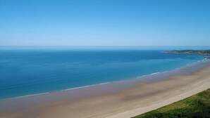 A coastal landscape with a wide sandy beach and calm sea under a clear blue sky. - Luxurious 4 bedroom apartment @Pickwell Manor on North Devon Coast near Croyde (Georgeham)