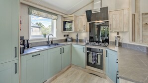 A modern kitchen with light green cabinets, a built-in oven, and a window with a view of greenery.