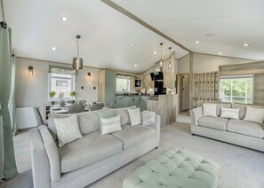 A modern living room with a sofa, ottoman, and dining area. - 2 bedroom accommodation in Woodhall Spa (Woodhall Spa)