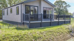 A modern mobile home with a deck, large windows, and a flat roof.