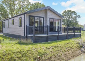 A modern mobile home with a deck, large windows, and a flat roof. - 2 bedroom accommodation in Woodhall Spa (Woodhall Spa)