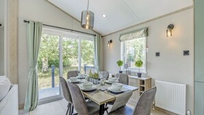 A dining area with a table set for four, chairs, a hanging light fixture, a window with a view, and a radiator.