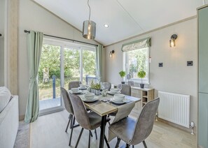 A dining area with a table set for four, chairs, a hanging light fixture, a window with a view, and a radiator. - 2 bedroom accommodation in Woodhall Spa (Woodhall Spa)