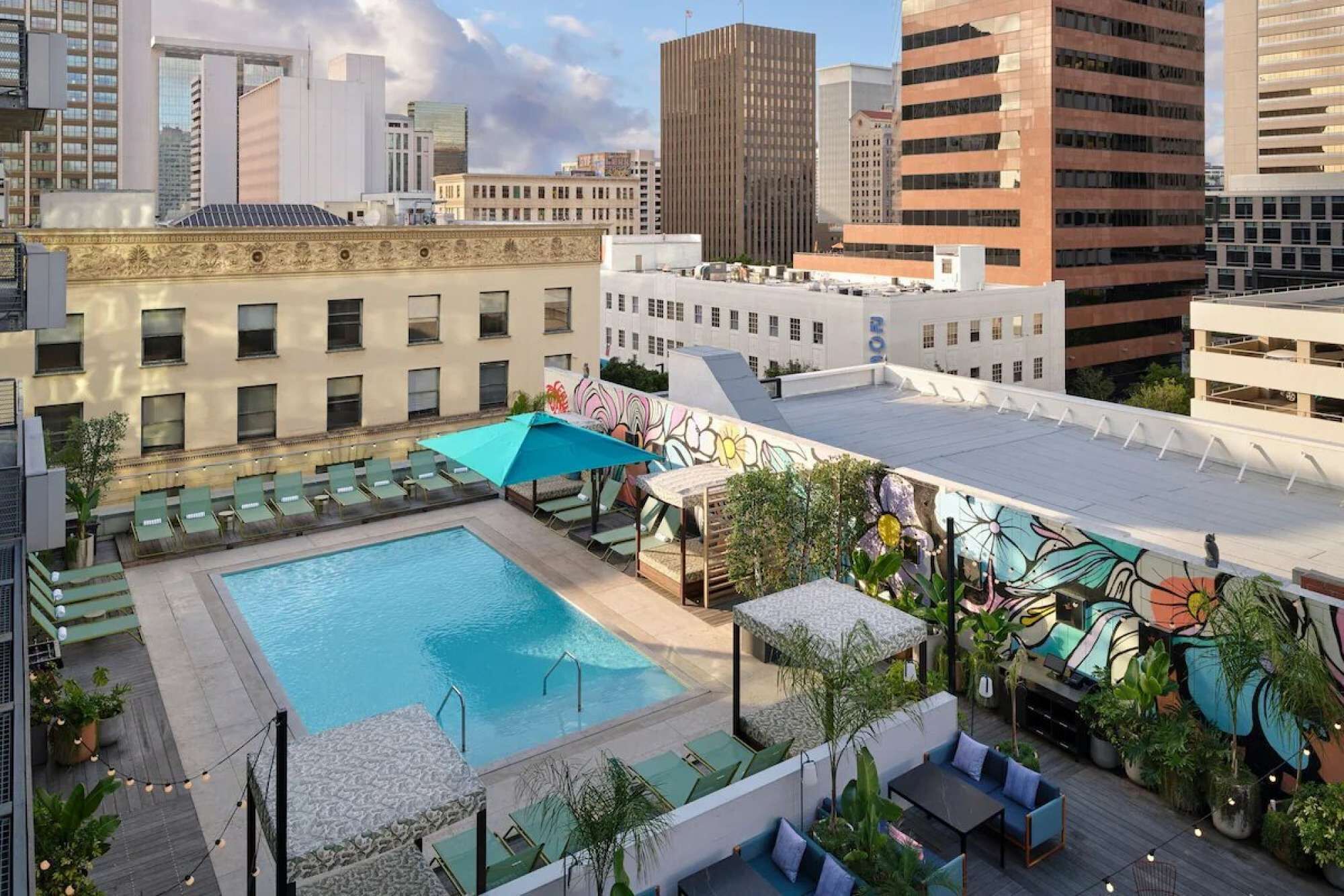 A rooftop pool area with a large pool, lounge chairs, and a mural.
