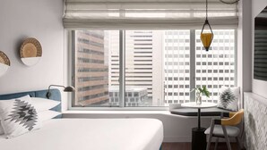 A modern bedroom with a large window, a bed, a small table, and a chair. - Walk to Gaslamp Quarter + Rooftop Pool & Dining (San Diego)