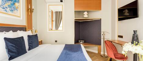 A hotel room with a large bed, a desk, a chair, a TV, and a mirror.