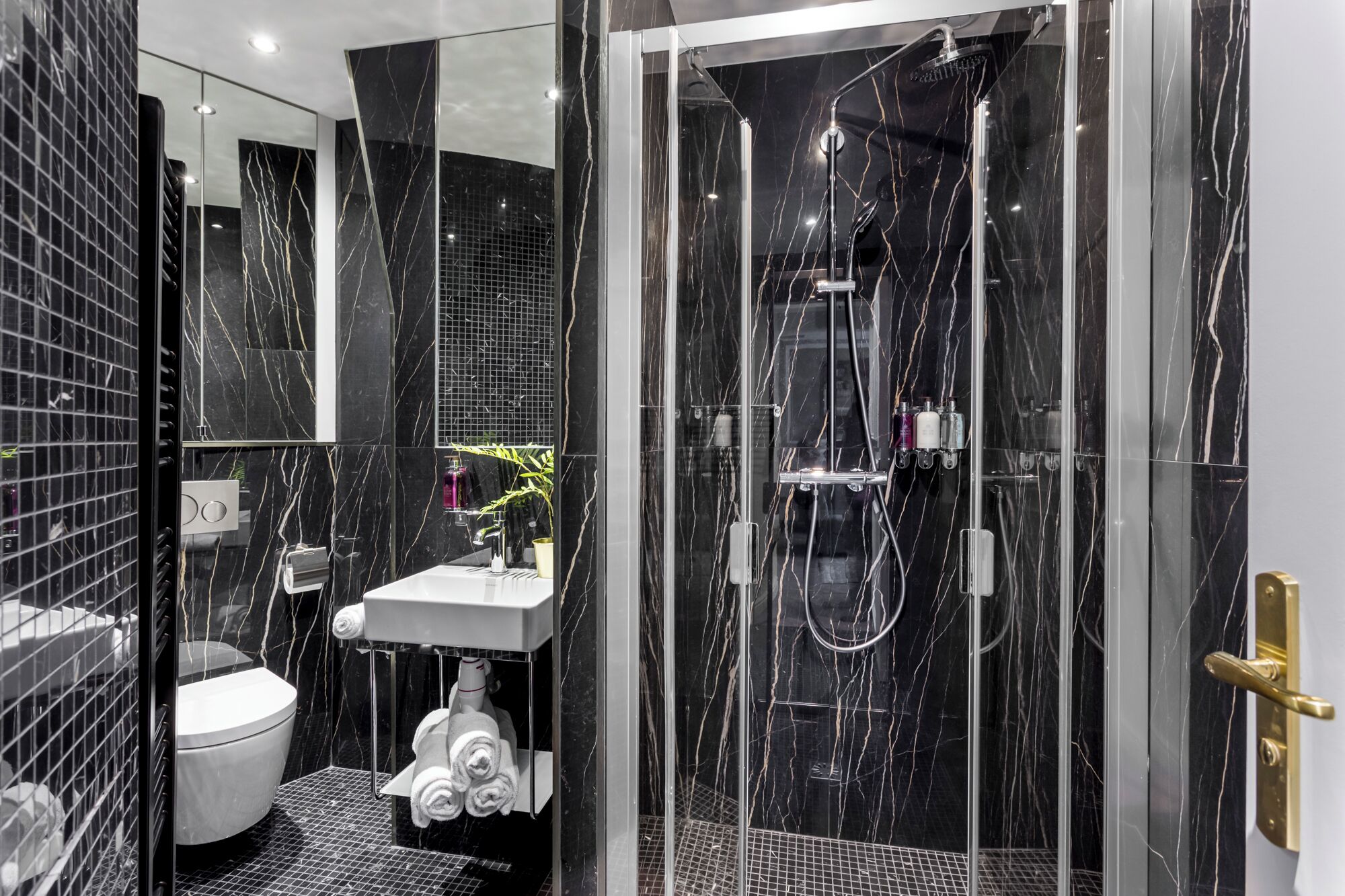 A modern bathroom with a glass-enclosed shower, a white sink, and a toilet.