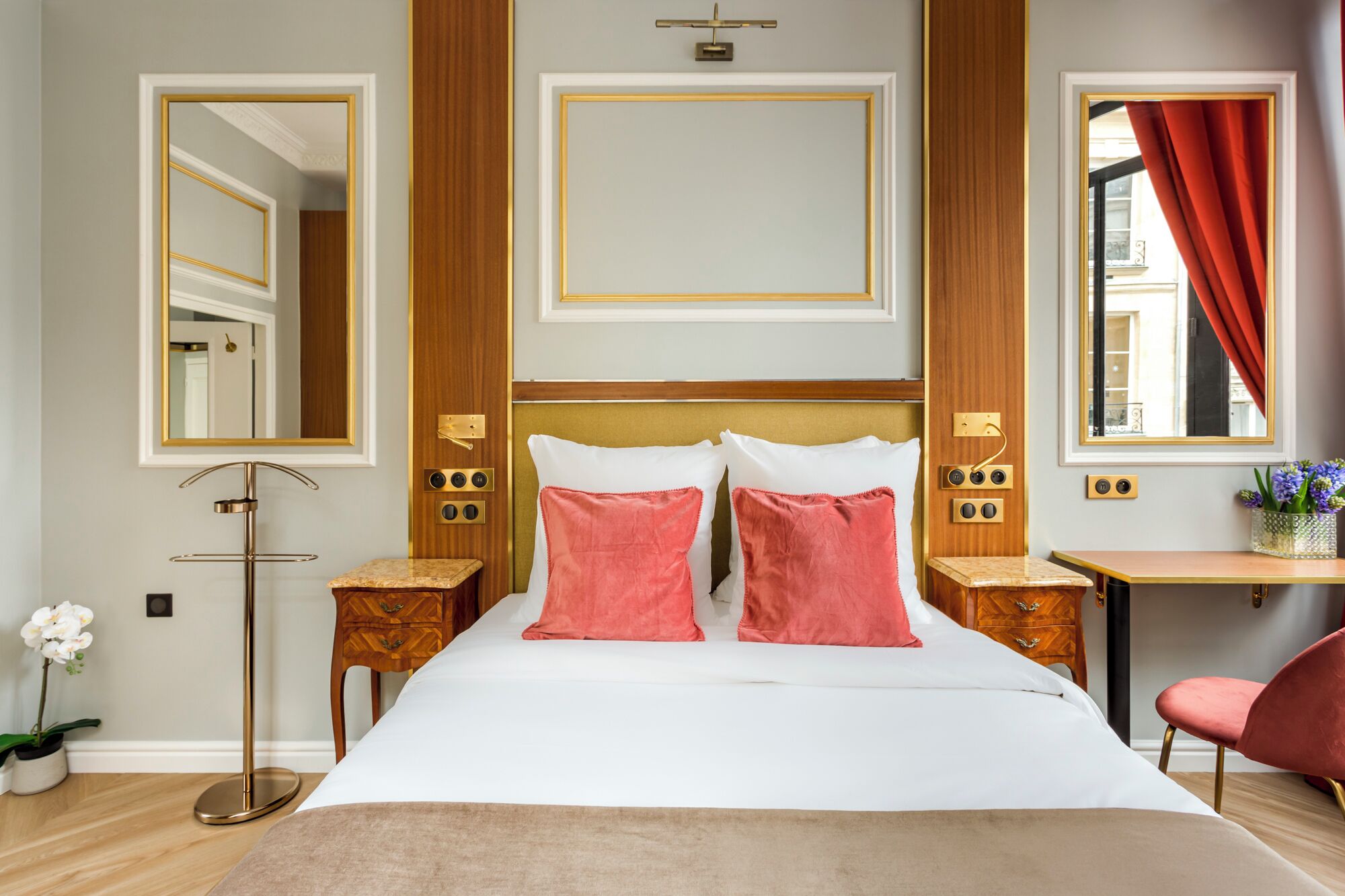 Ein Hotelzimmer mit einem großen Bett, zwei Nachttischen, einem Schreibtisch, einem Stuhl und einem Vorhangfenster.
