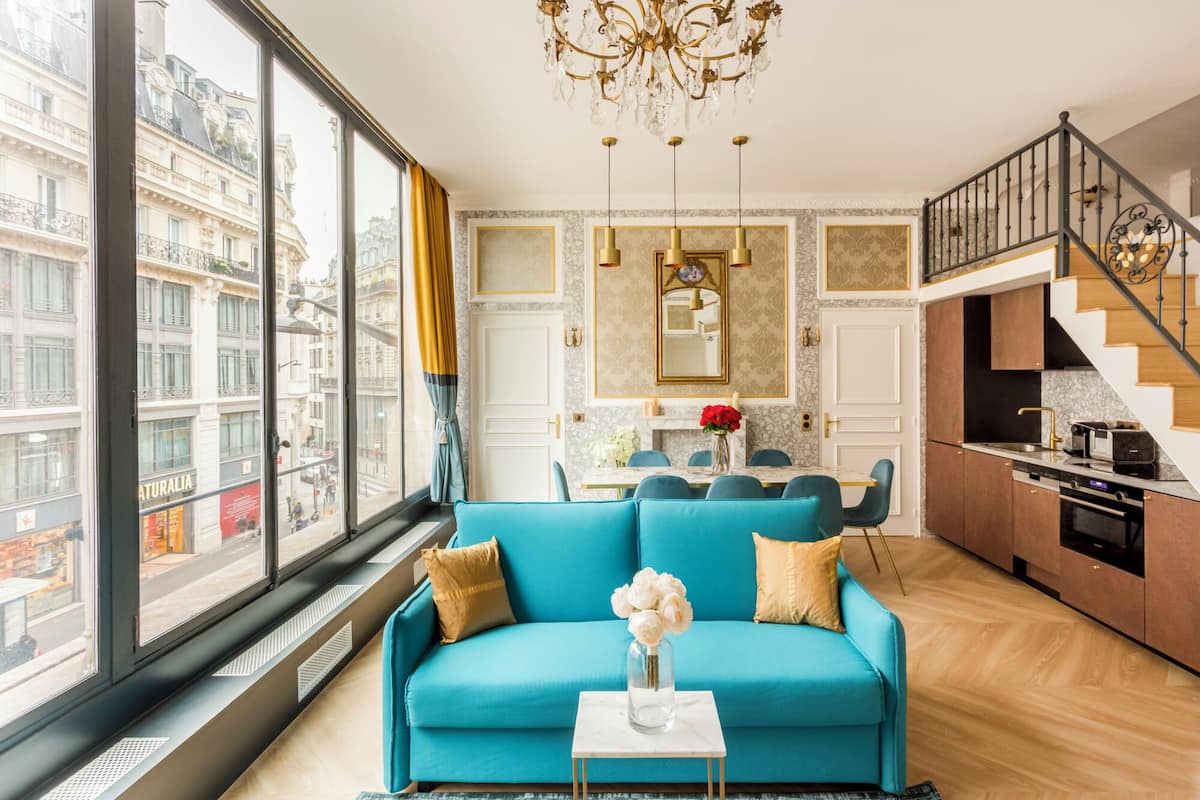 Uma sala de estar moderna com um sofá azul, área de refeições e cozinha.