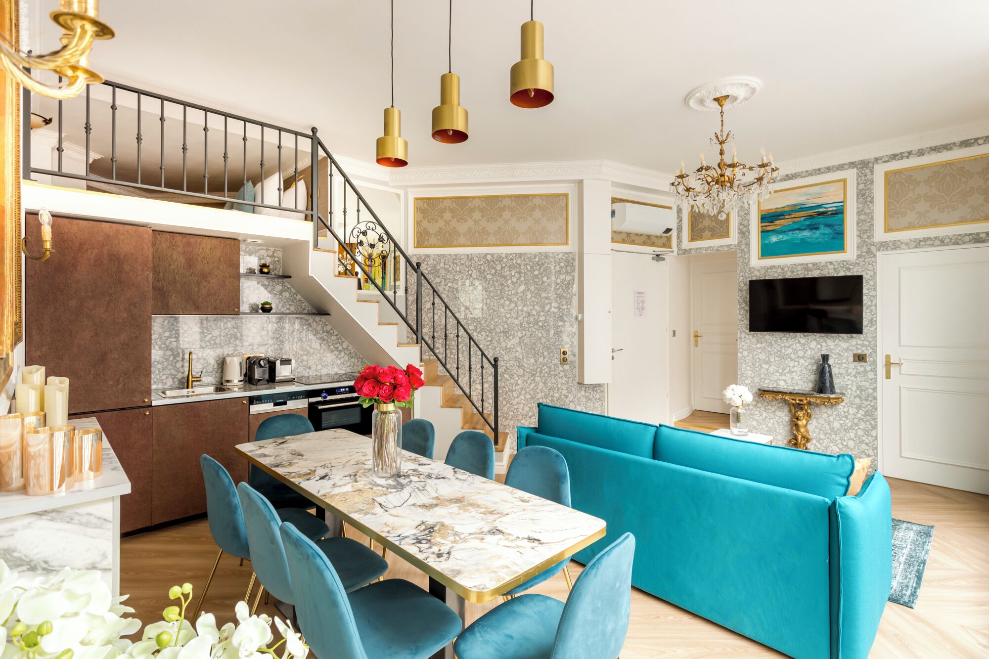 Una cocina moderna con encimera de mármol, una zona de comedor con mesa de mármol y un sofá azul brillante.