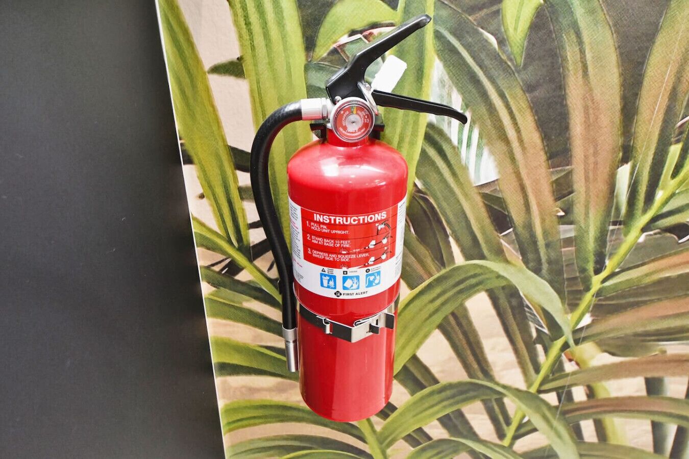 Een rode brandblusser aan een muur bevestigd, met instructies en veiligheidssymbolen.