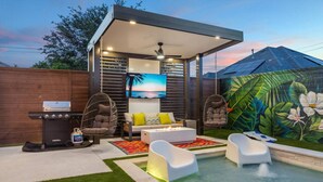 A backyard with a pool, a barbecue grill, hanging chairs, a sofa, and a mural. - `Bali in Houston`/8BR/8Bath/Heated Pool/Sleeps 23 (Houston)