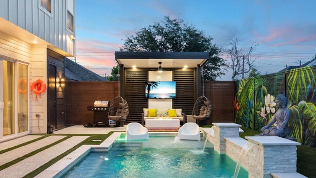 A modern outdoor pool area with a seating area, a barbecue setup, and a mural on the wall. - `Bali in Houston`/8BR/8Bath/Heated Pool/Sleeps 23 (Houston)