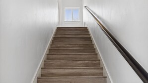 A wooden staircase with white walls and a window at the top.