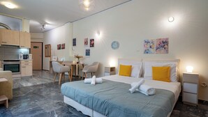 A hotel room with a bed, bedside tables, a desk, chairs, a kitchenette, and a bathroom. - Plaka City Studio – Walk to Syntagma by ΜΡS (Athina)