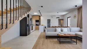 A modern living room with a sofa, coffee table, and a staircase with wooden railings. - Villa Alba Zadarvillas (Pakostane)
